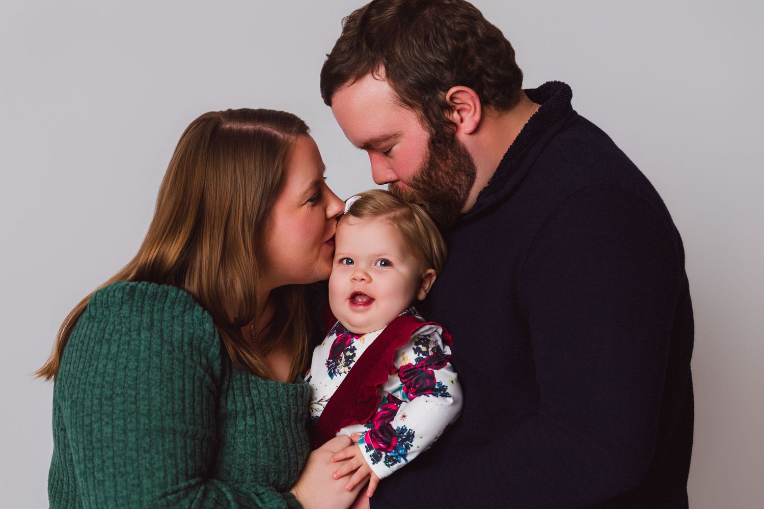 Family wearing green and black sweaters poses together in a series of candid lifestyle portraits.