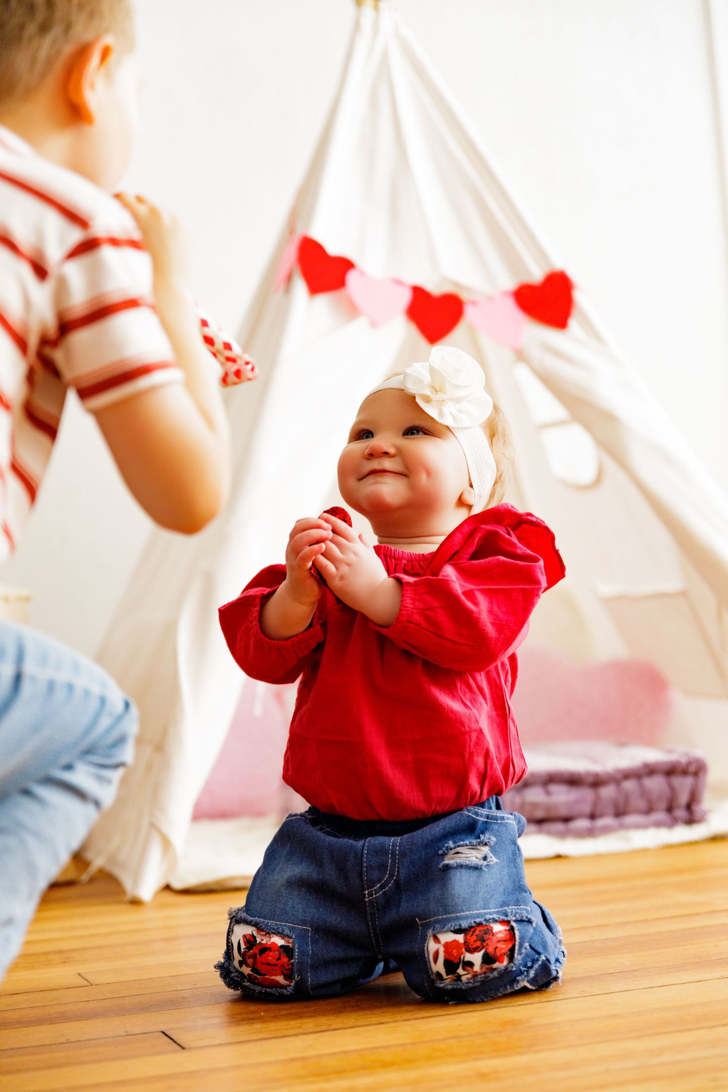 Series of photos showing movement on hardwood floor with white teepee and heart decorations.