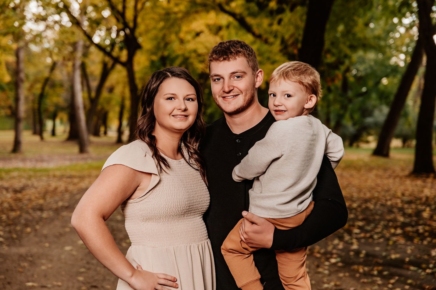 A family shares a warm moment together in an autumn park setting with golden leaves.