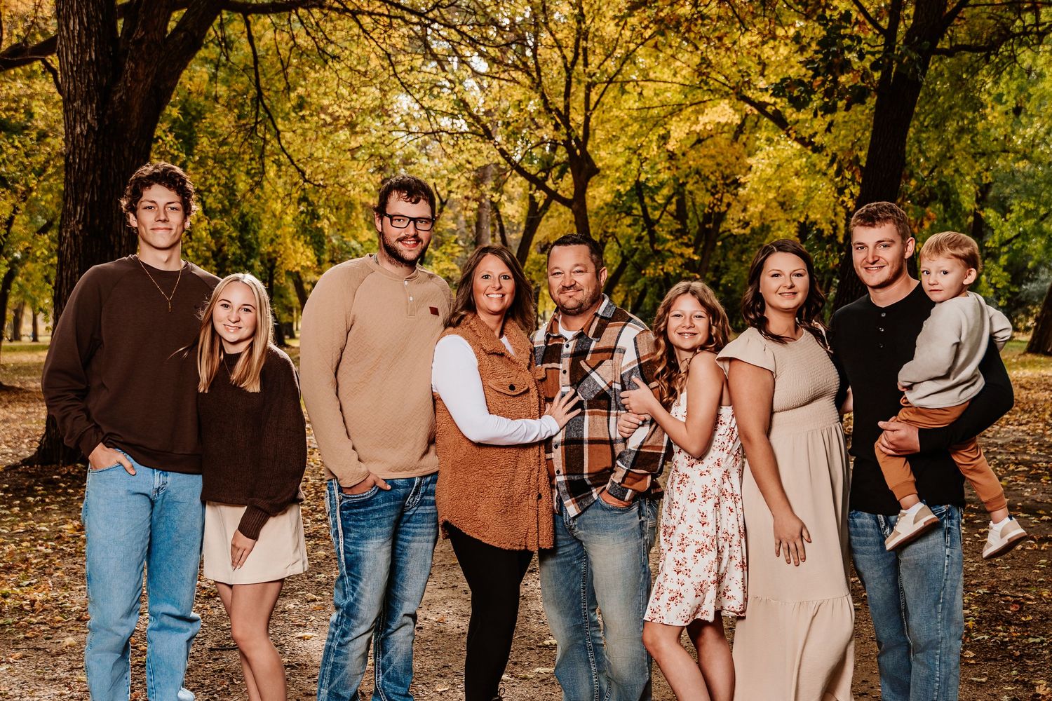 Group of friends laughing together during autumn photoshoot in park with golden fall foliage.
