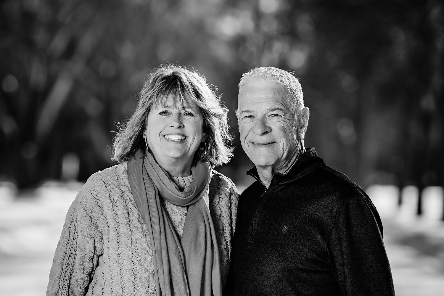 A couple shares a warm moment together outdoors in black and white photography.