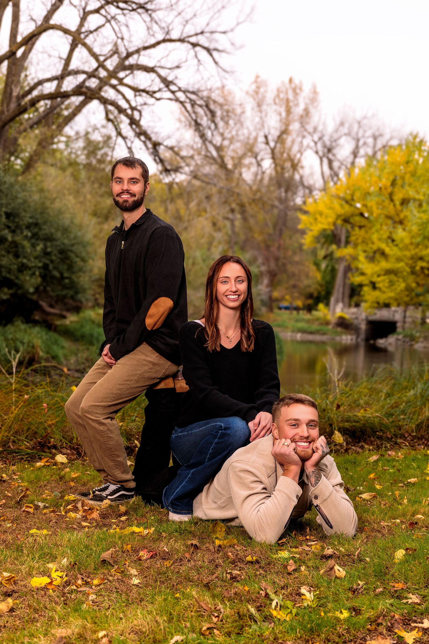 Family group lounging on autumn leaves for casual outdoor portrait session.