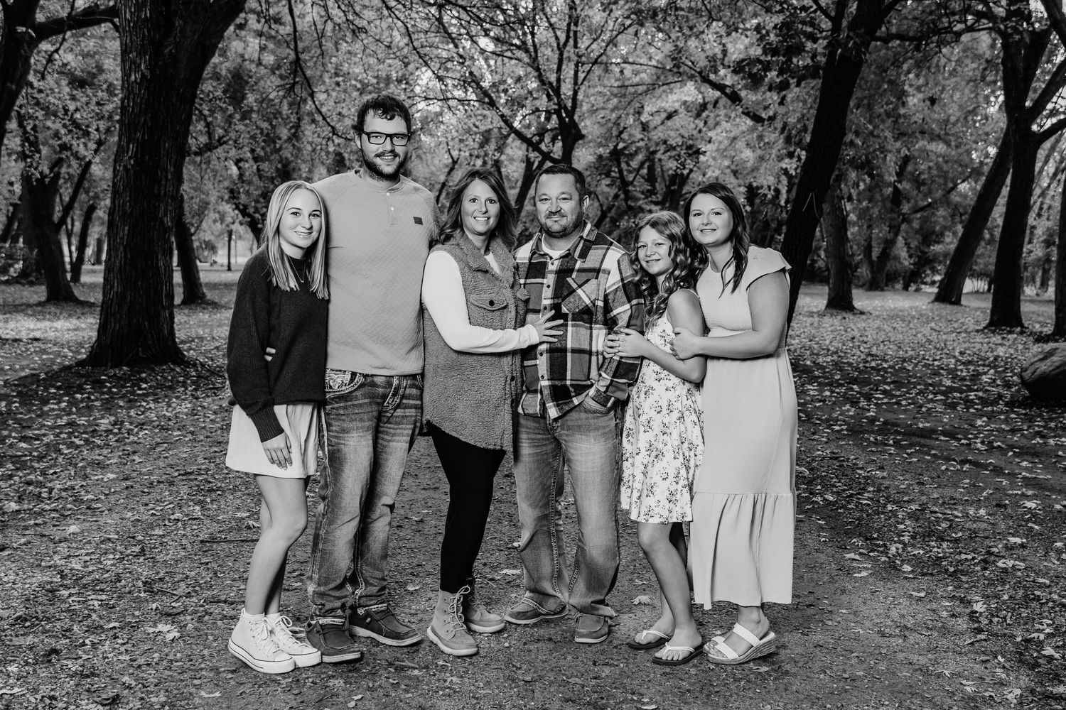 A group of people standing together in a wooded area captured in black and white photography.