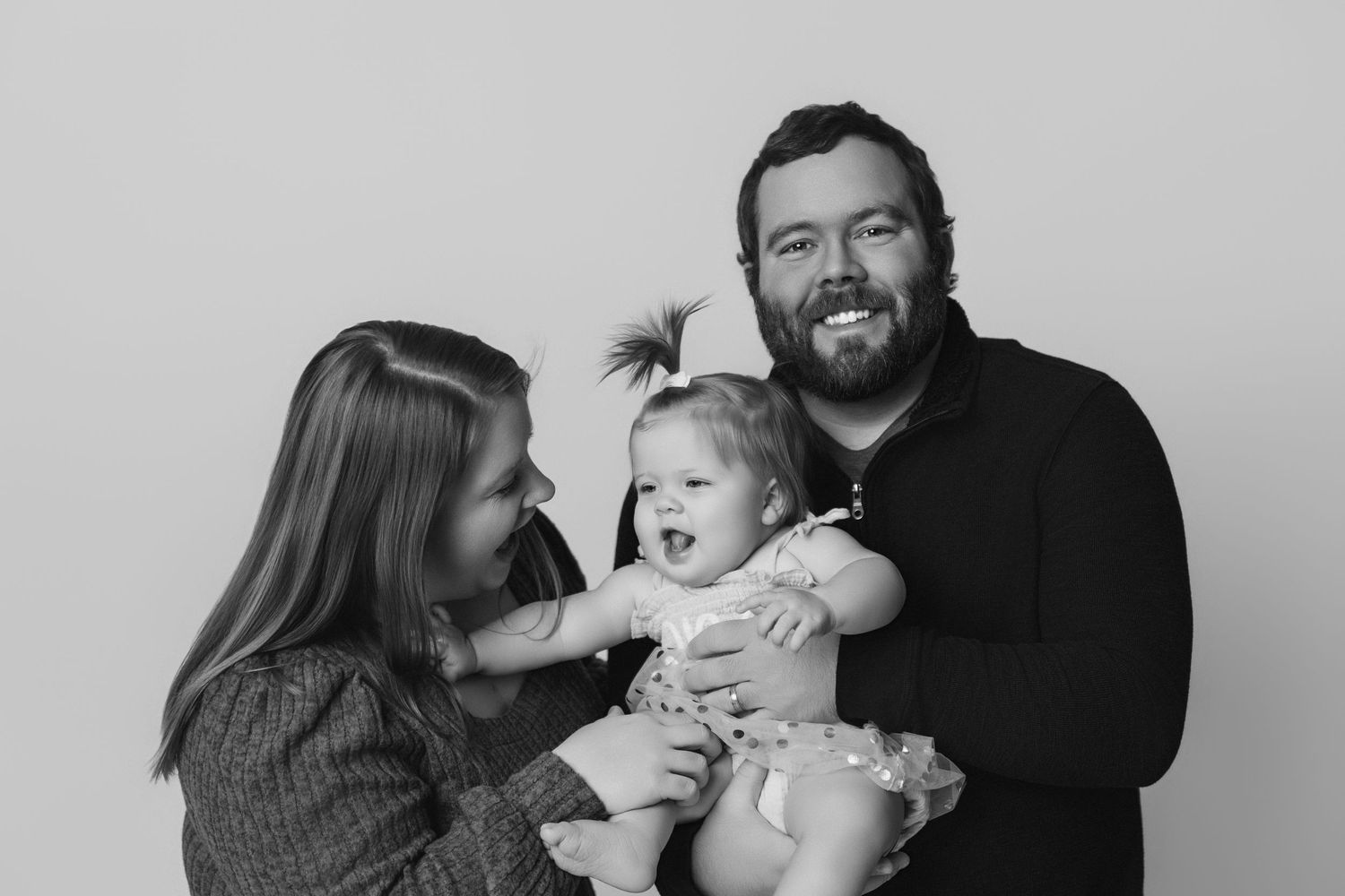 Black and white family portraits showing tender moments with baby.
