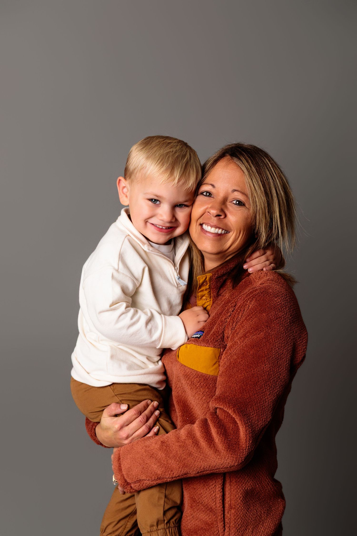 Heartwarming portraits showing tender moments in a rust-colored sweater against a grey background.