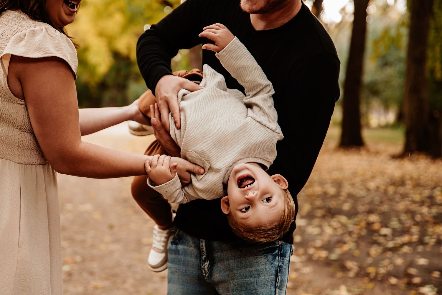 Playful family moment captured in golden autumn forest setting.