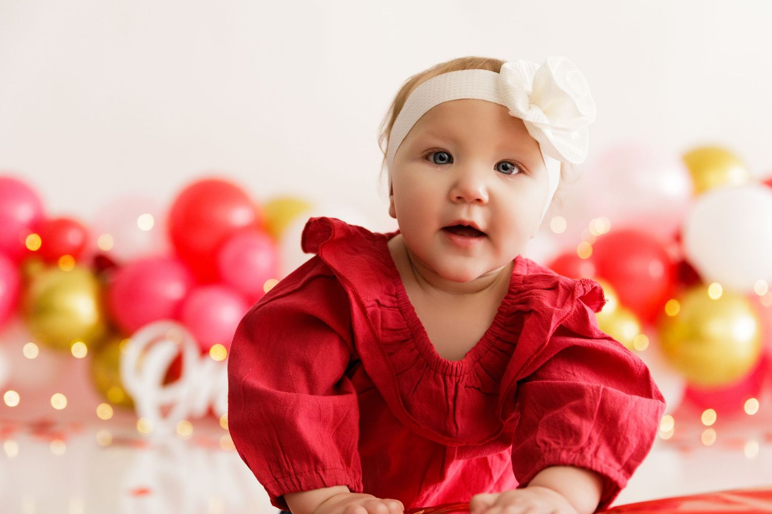 Red and white themed first birthday celebration with balloon decorations.
