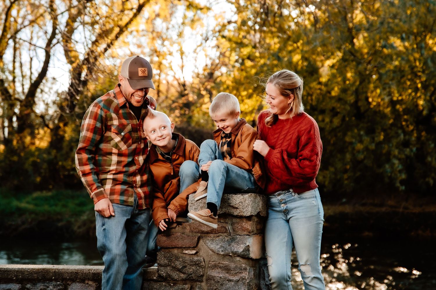 A family in plaid shirts and jeans share joyful moments together during a golden hour photoshoot in nature.