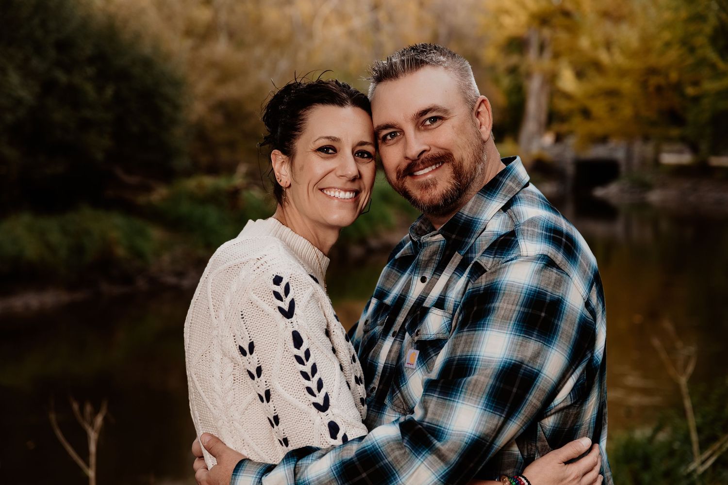 A couple shares tender moments outdoors during a golden hour photo session in a natural setting.