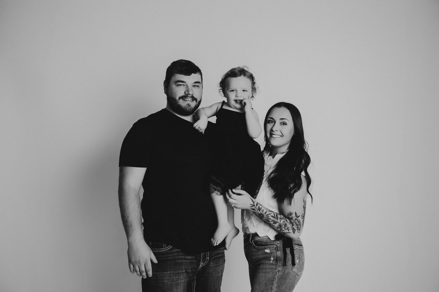 A collection of black and white family portraits showing parents and children in casual poses against neutral backgrounds.