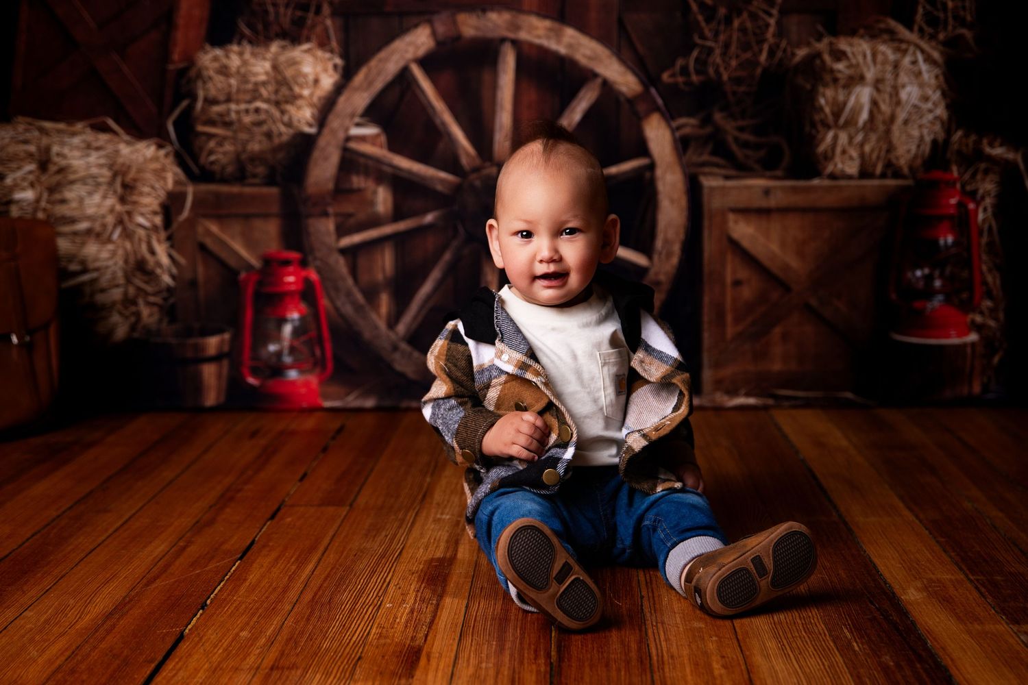 A small figure in blue jeans sits on wooden floor with rustic wagon wheel and lantern decor in background.