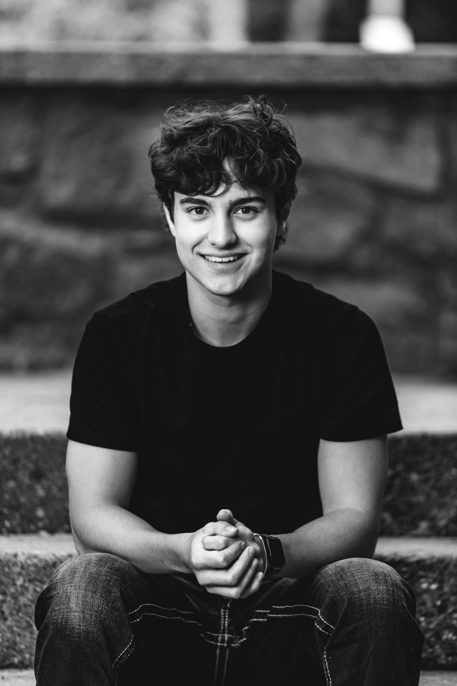 Black and white photo series showing someone sitting outdoors wearing a dark t-shirt with a warm smile.