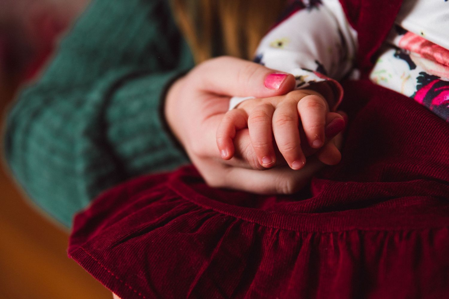 Close-up of tiny hands against burgundy fabric in studio lighting.
