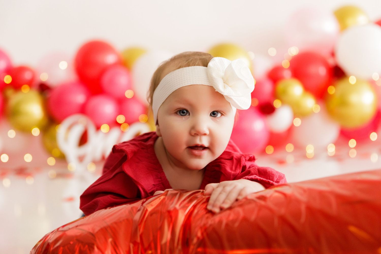 Valentine's day themed photo setup with red and gold balloons and white 'one' text decoration.
