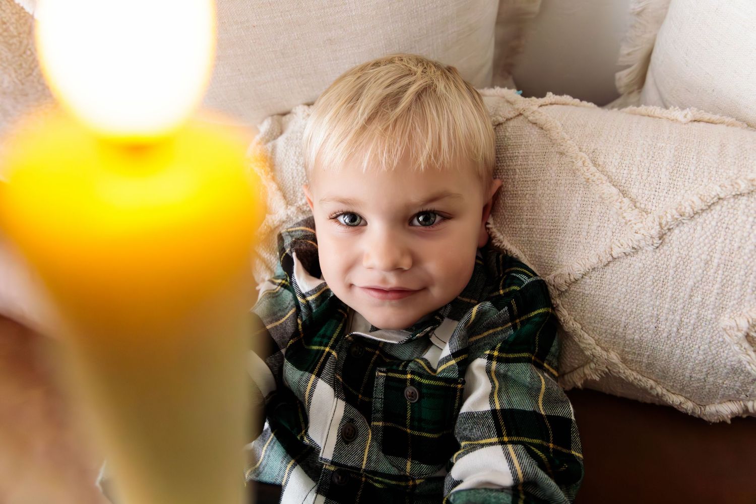 Cozy indoor portrait with warm lighting and candles creating soft atmosphere.