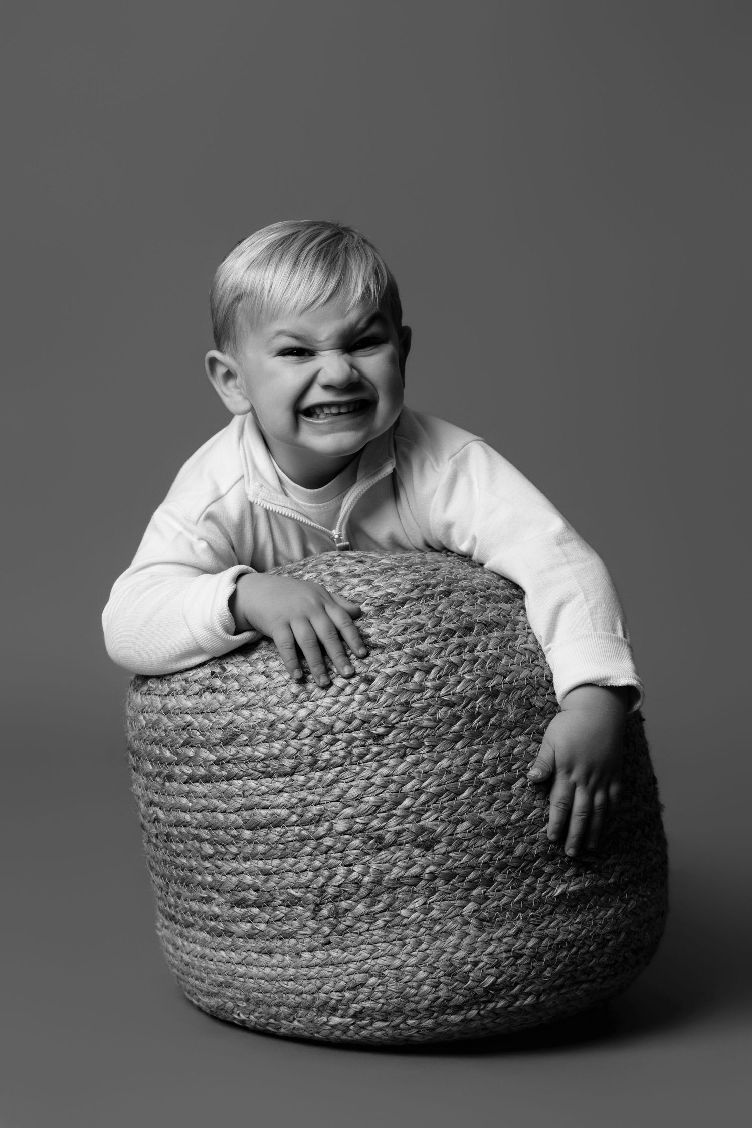Black and white photo series showing playful moments with a woven basket against a gray background.