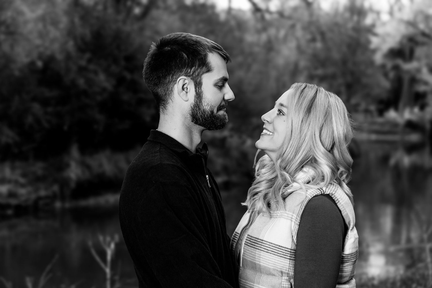 Black and white portrait of couple sharing intimate moment outdoors.