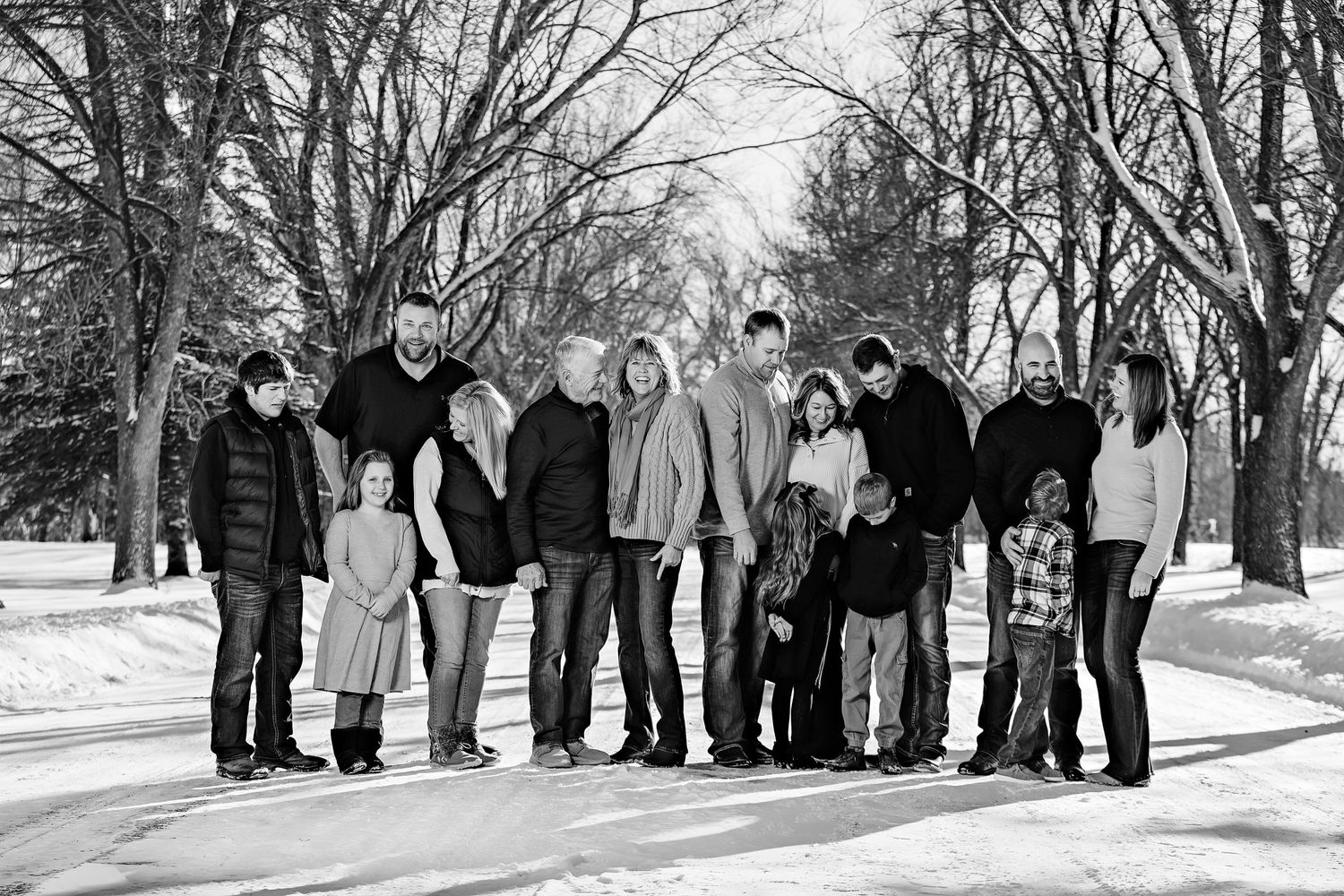 A group of people walking together on a snowy path lined with bare winter trees.