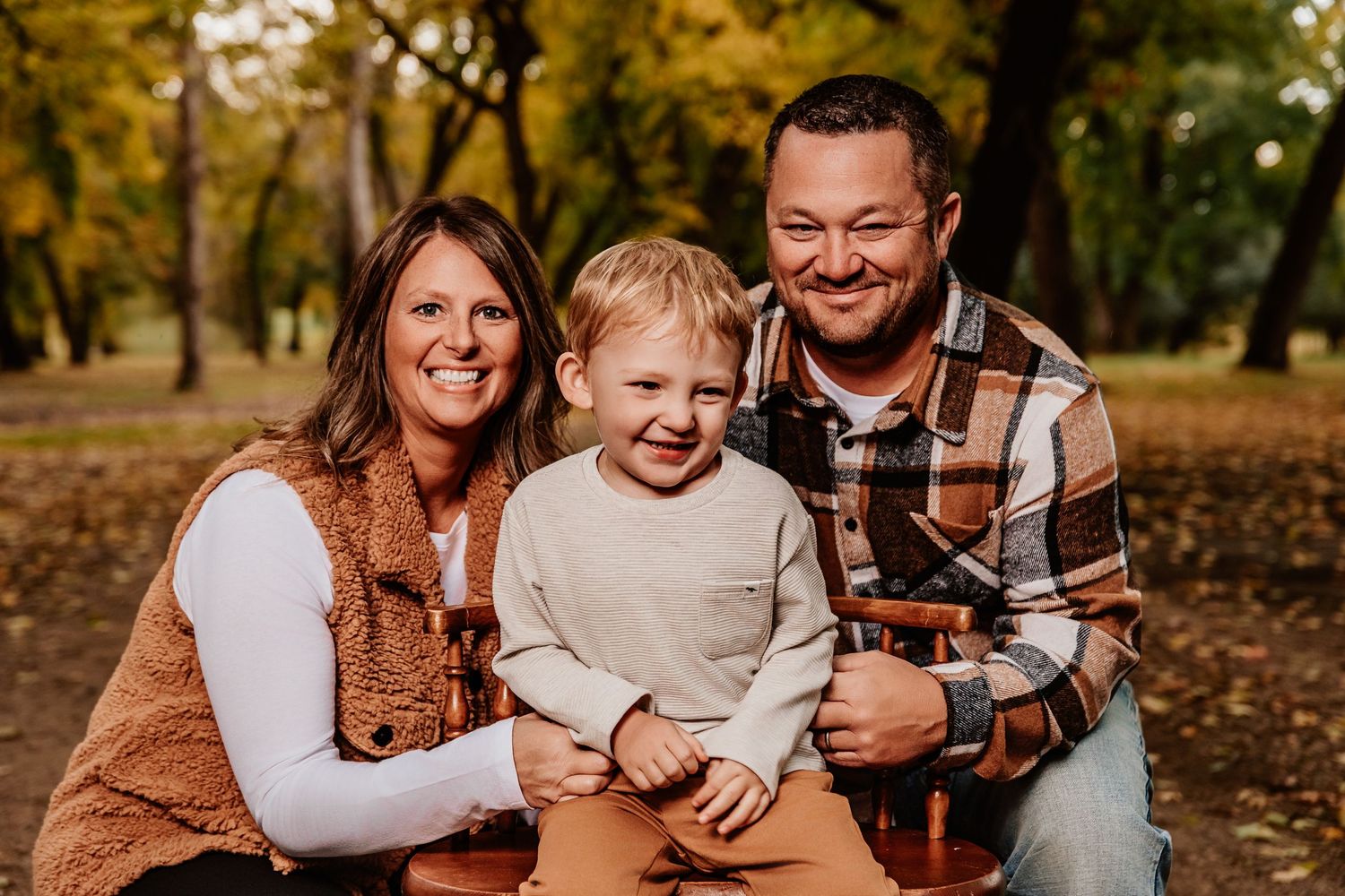 A family shares joyful moments together on fallen autumn leaves.