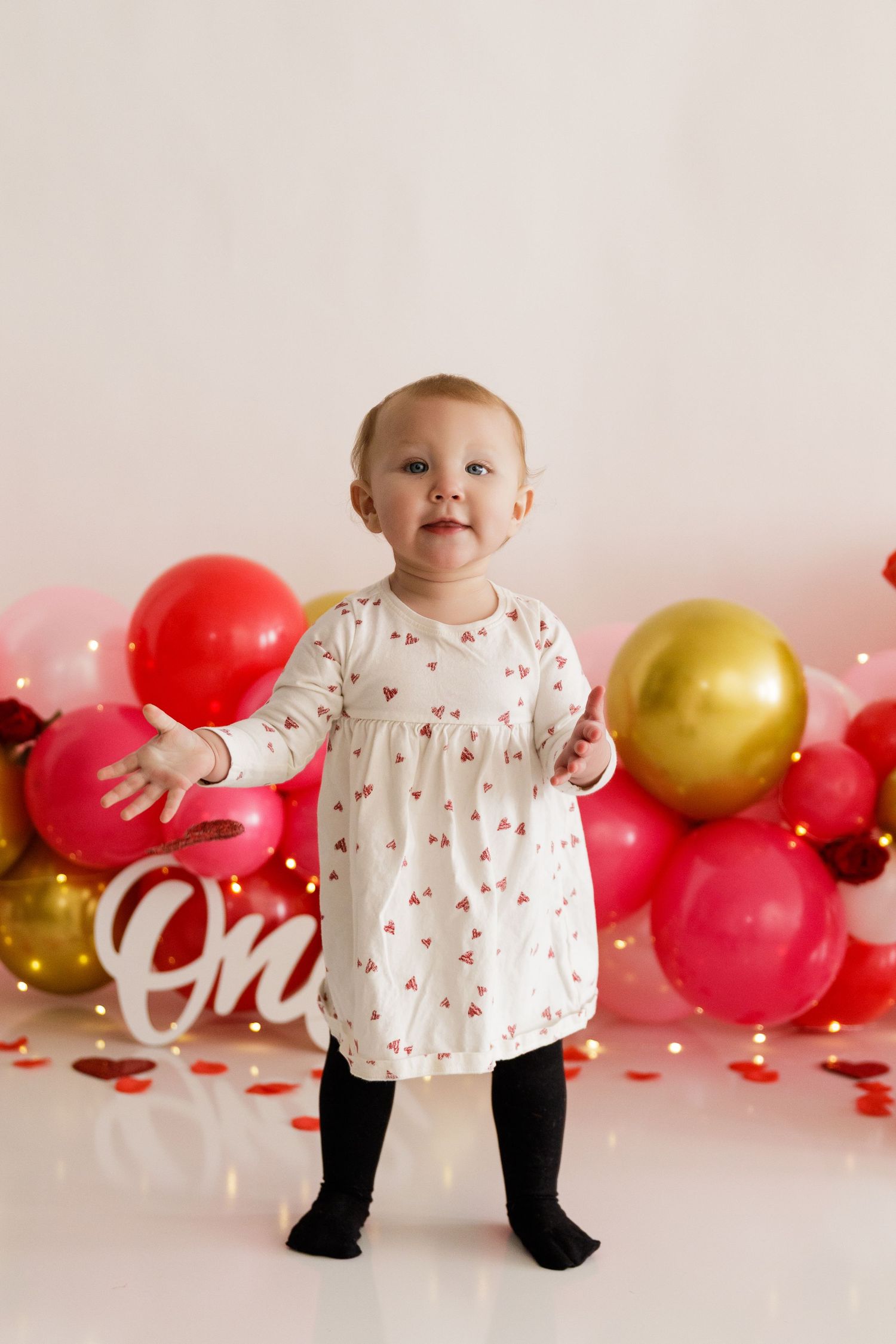 Valentine's themed photo setup with red and gold balloons against white background.