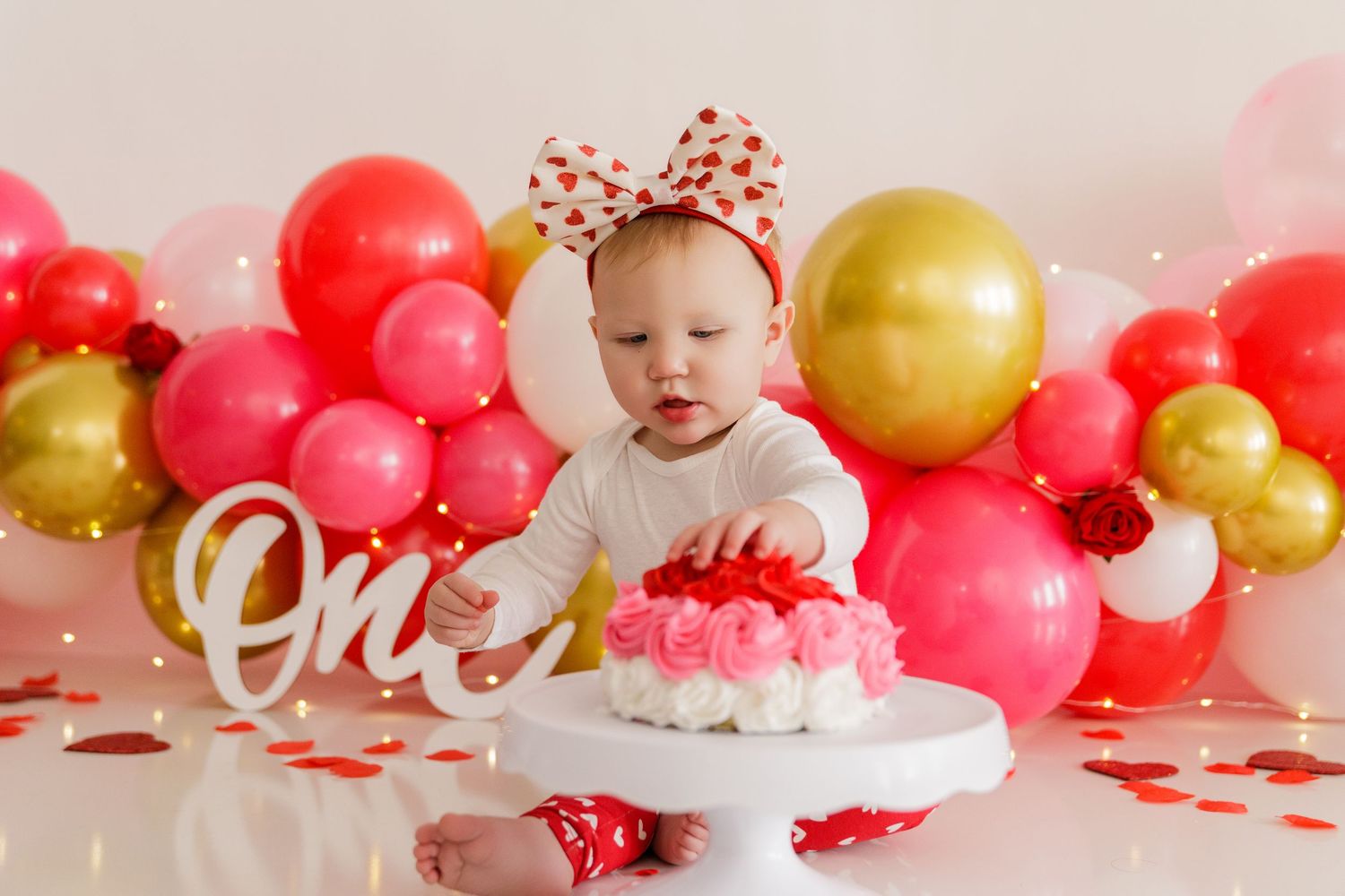 Valentine's Day photo setup with pink and gold balloons against a white backdrop.
