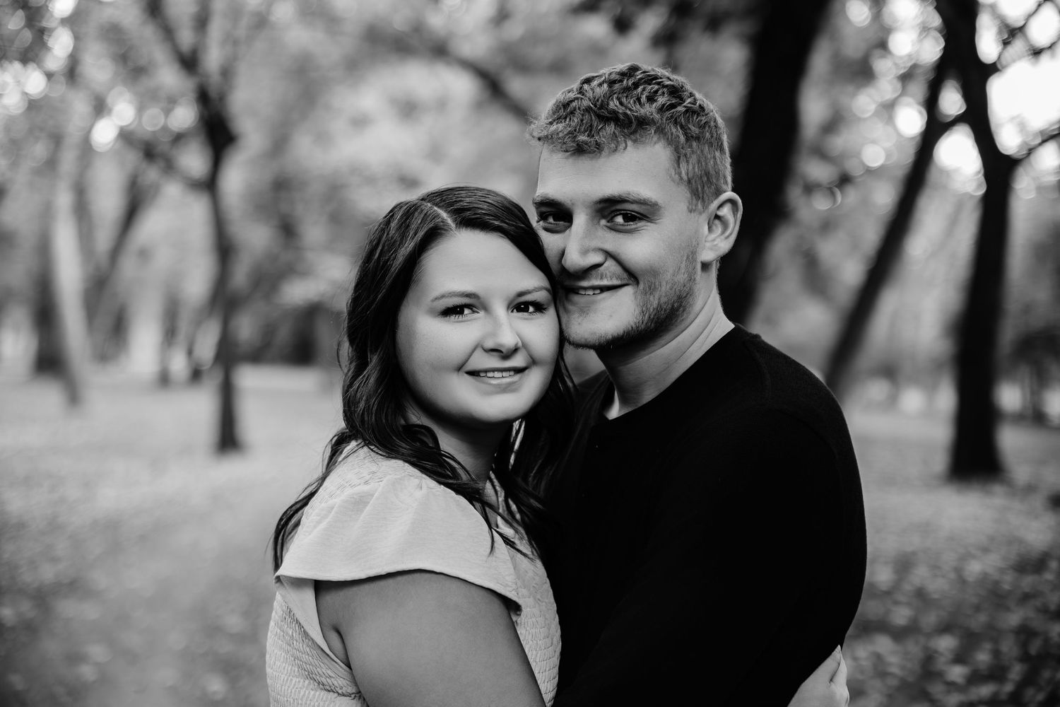 Black and white portrait capturing tender moments between loved ones in a natural setting.