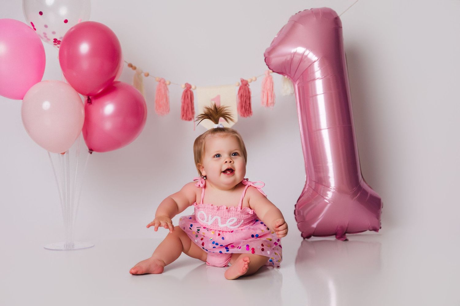 First birthday celebration setup with pink balloons and decorations.