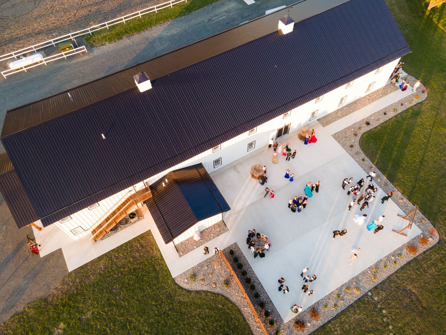 Aerial drone view of a skate park with ramps and rails surrounded by grass and fencing.