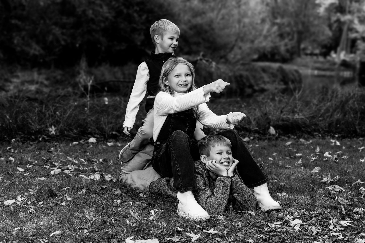 Black and white candid family moments captured on fallen leaves in park setting.