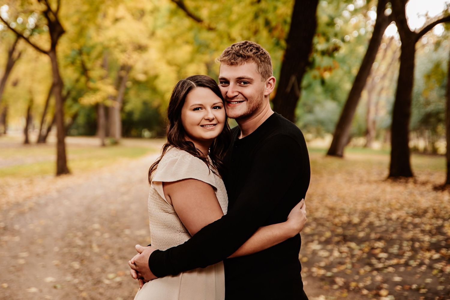 Family embracing and sharing joyful moments during autumn photo session in a park.