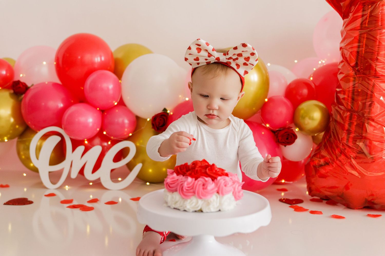Pink and gold balloon arch with 'One' sign creating a festive first birthday backdrop.