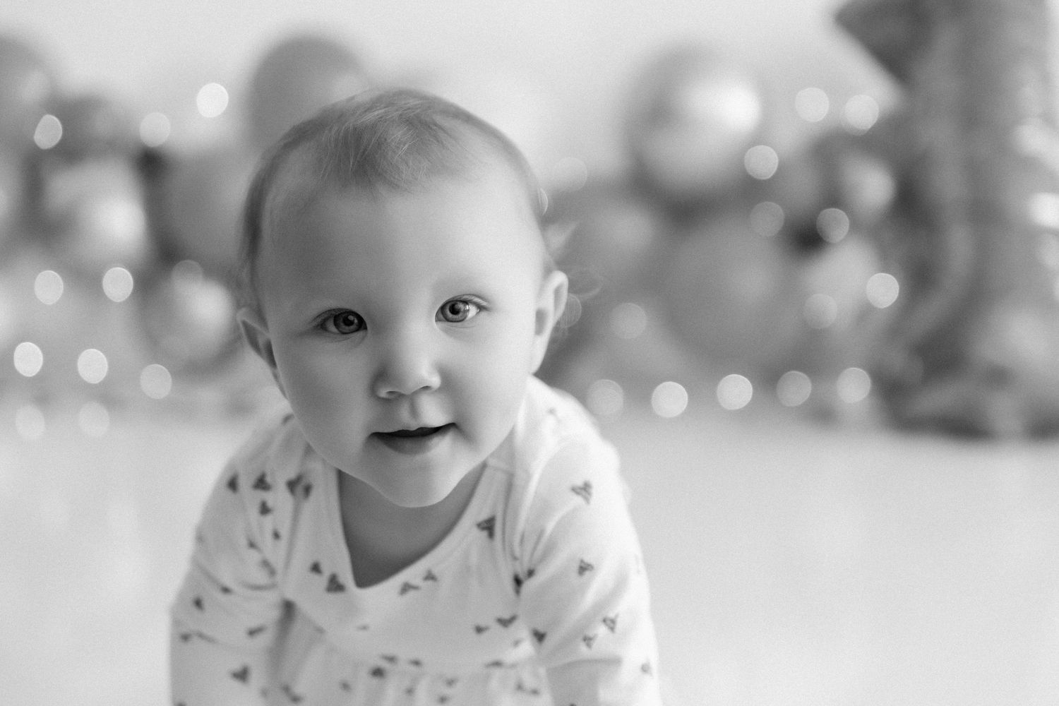 Black and white portrait showing joyful expression against bright bokeh background.