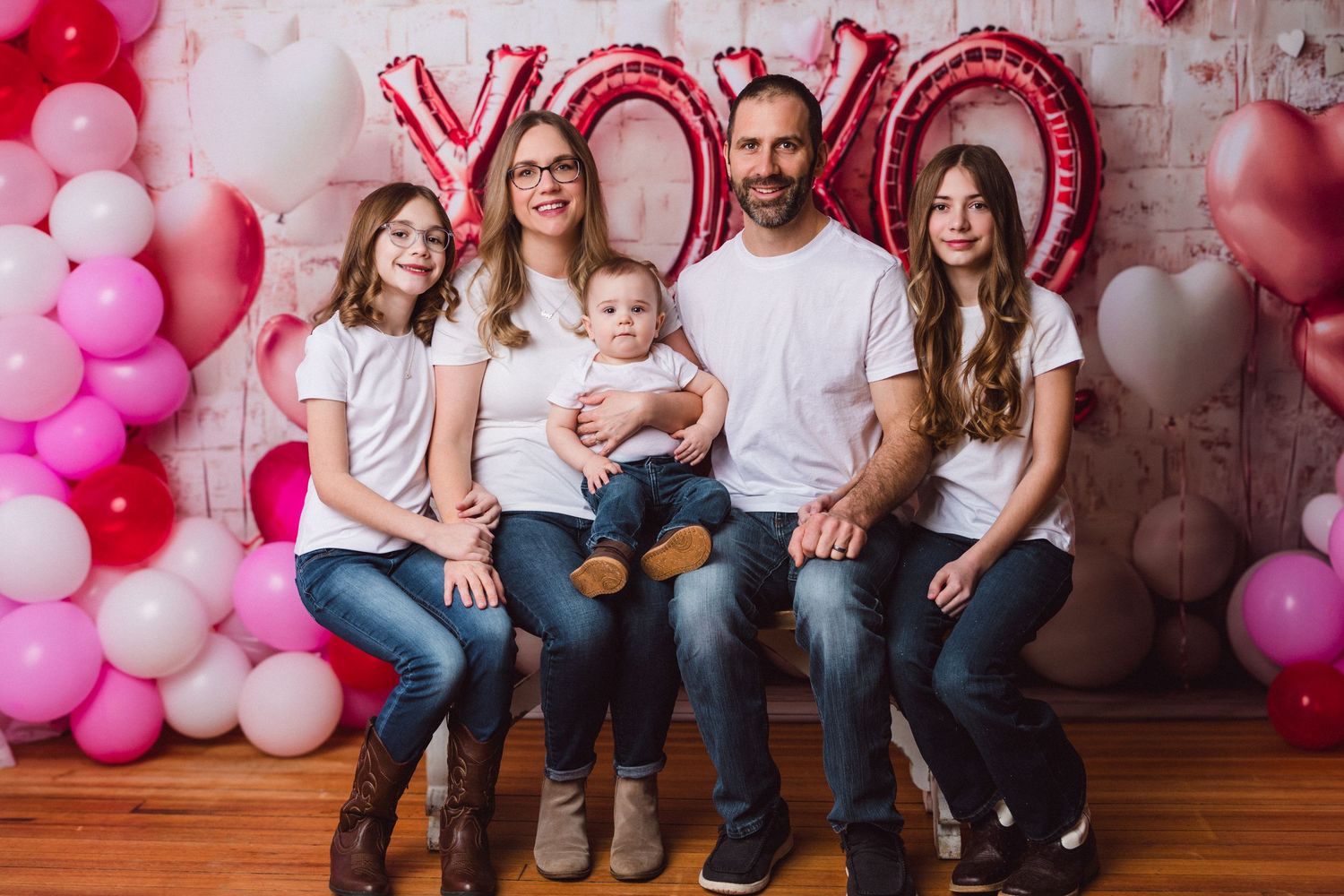 Family portrait in front of pink balloon arch and XOXO balloon letters for Valentine's Day photo session.