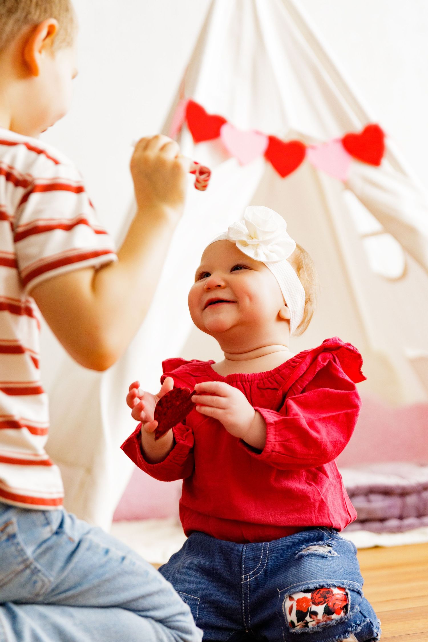 Joyful moment captured with red outfit and heart decorations under white teepee.