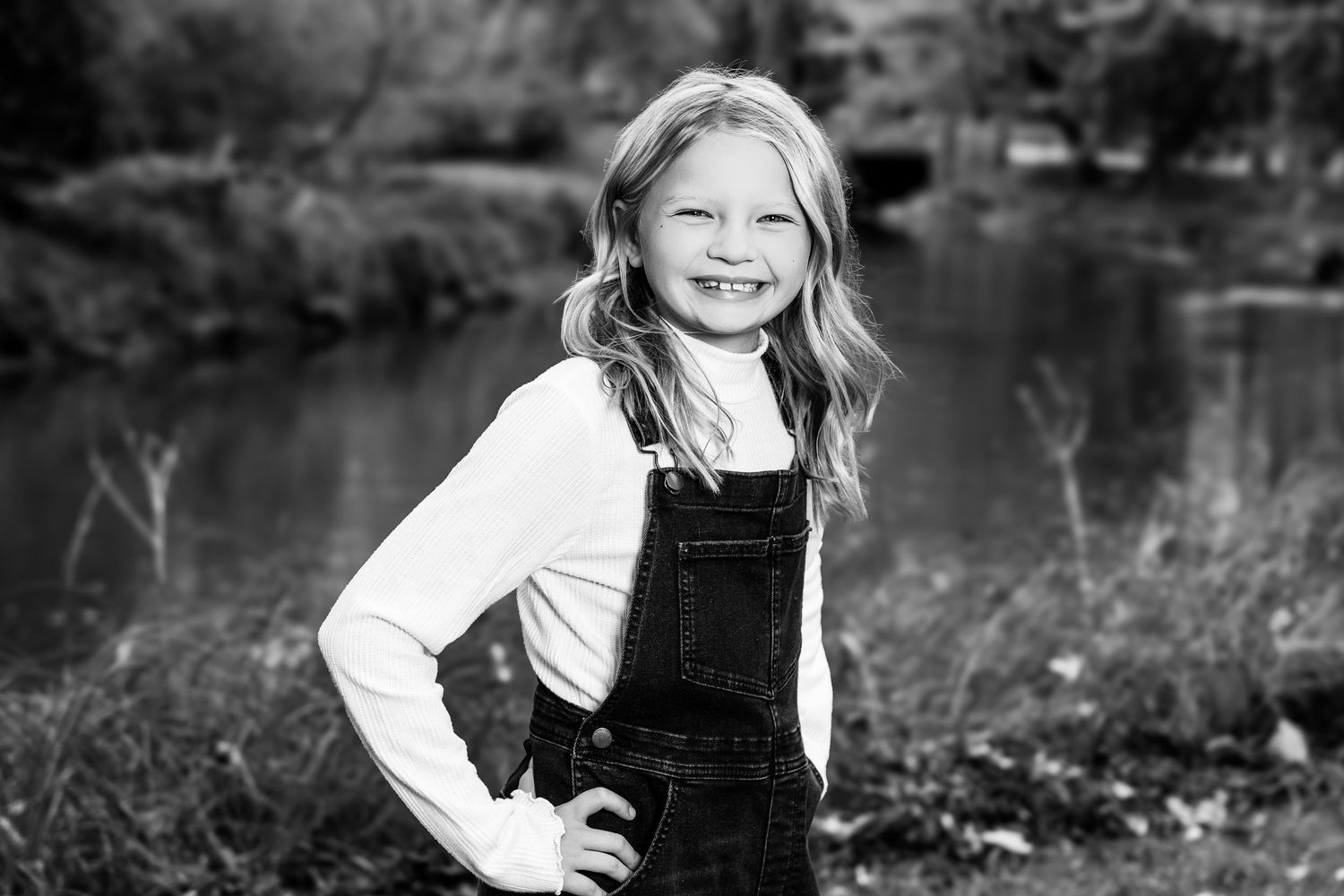 A black and white portrait photo taken outdoors with a natural background.