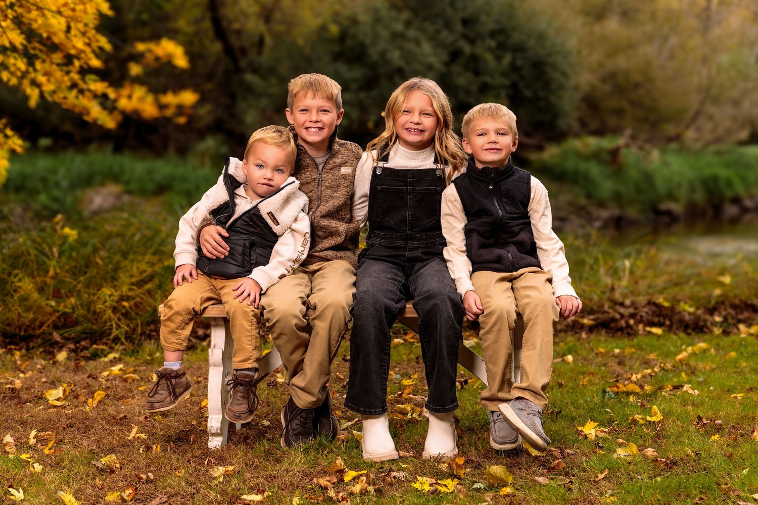 People relaxing on colorful fall leaves while wearing matching khaki and white clothing in nature.