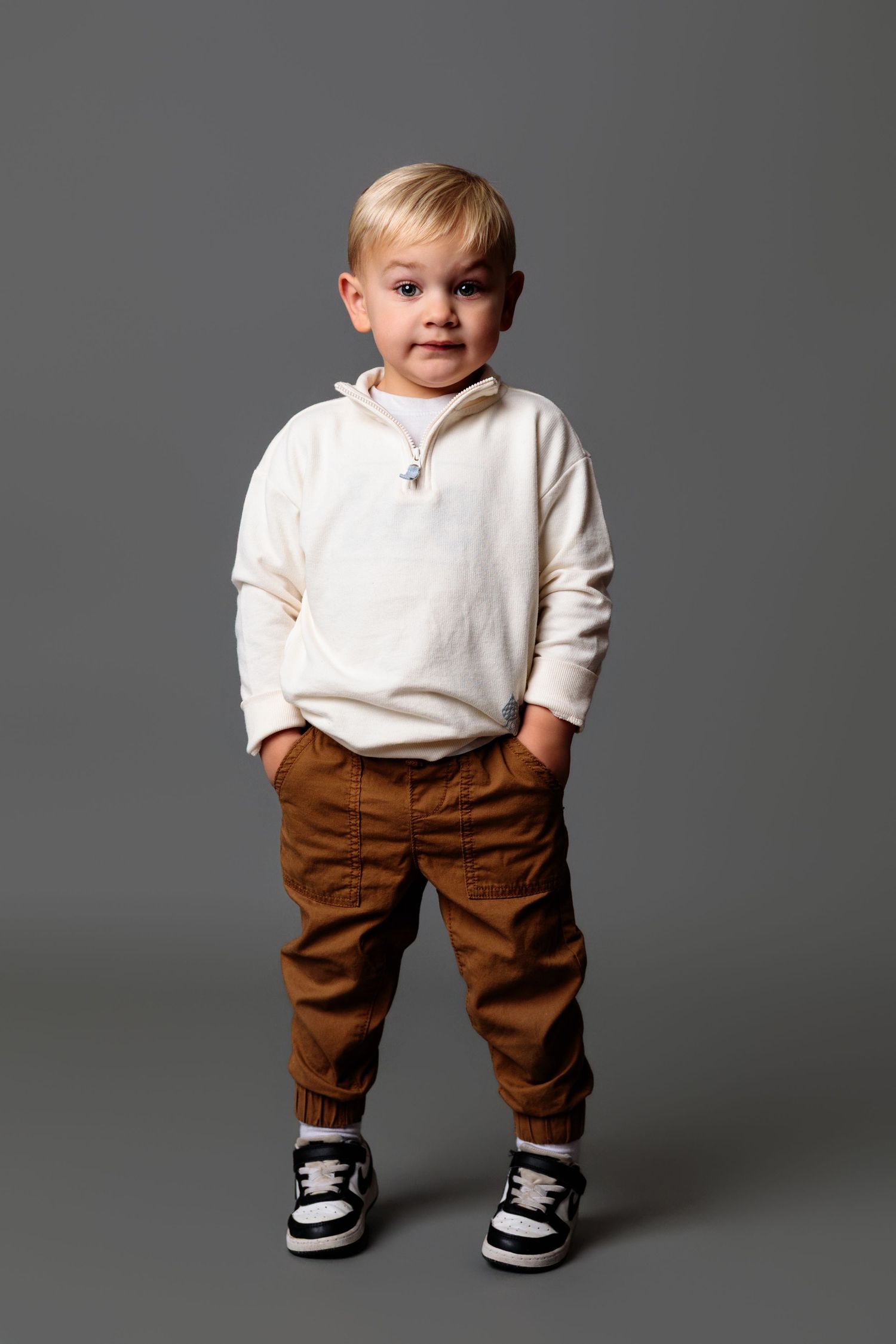 A toddler in casual attire stands against a gray background showing their outfit.