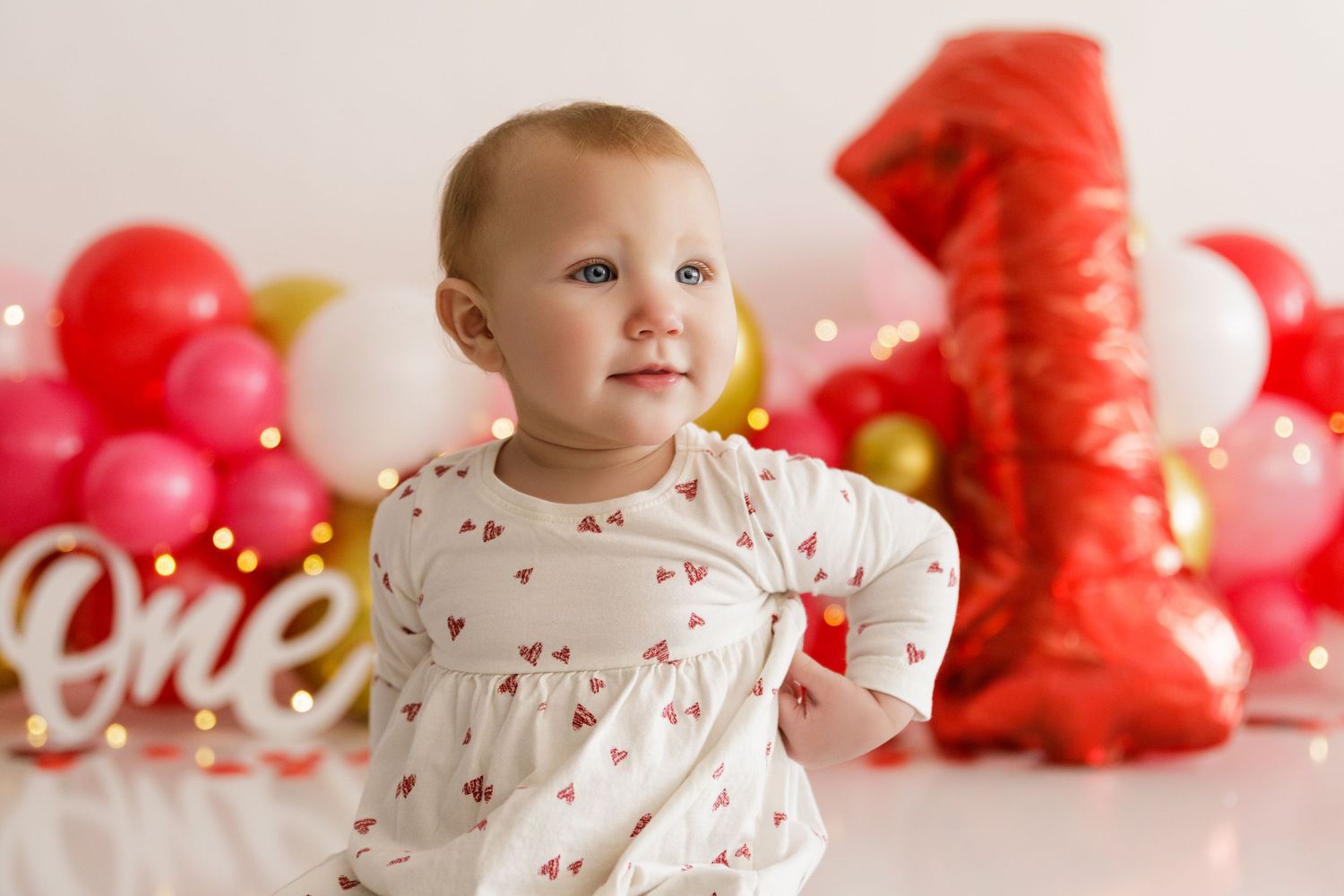 Festive birthday setup with pink and gold balloons and a large red number one balloon.
