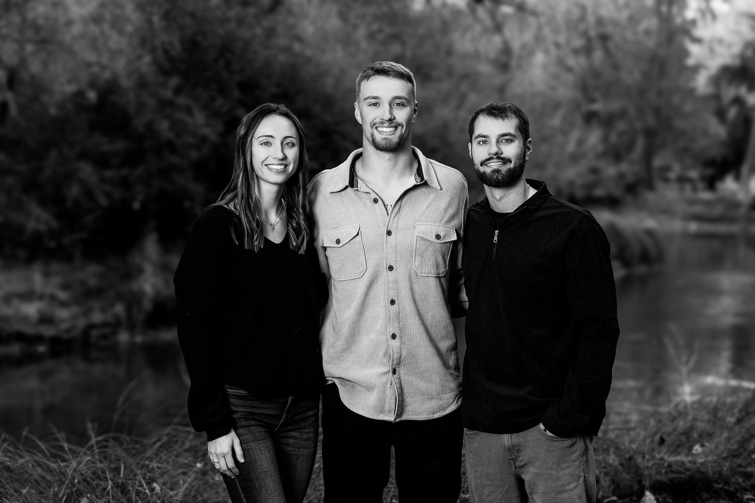 Group photo of people in casual attire standing together outdoors during fall season.