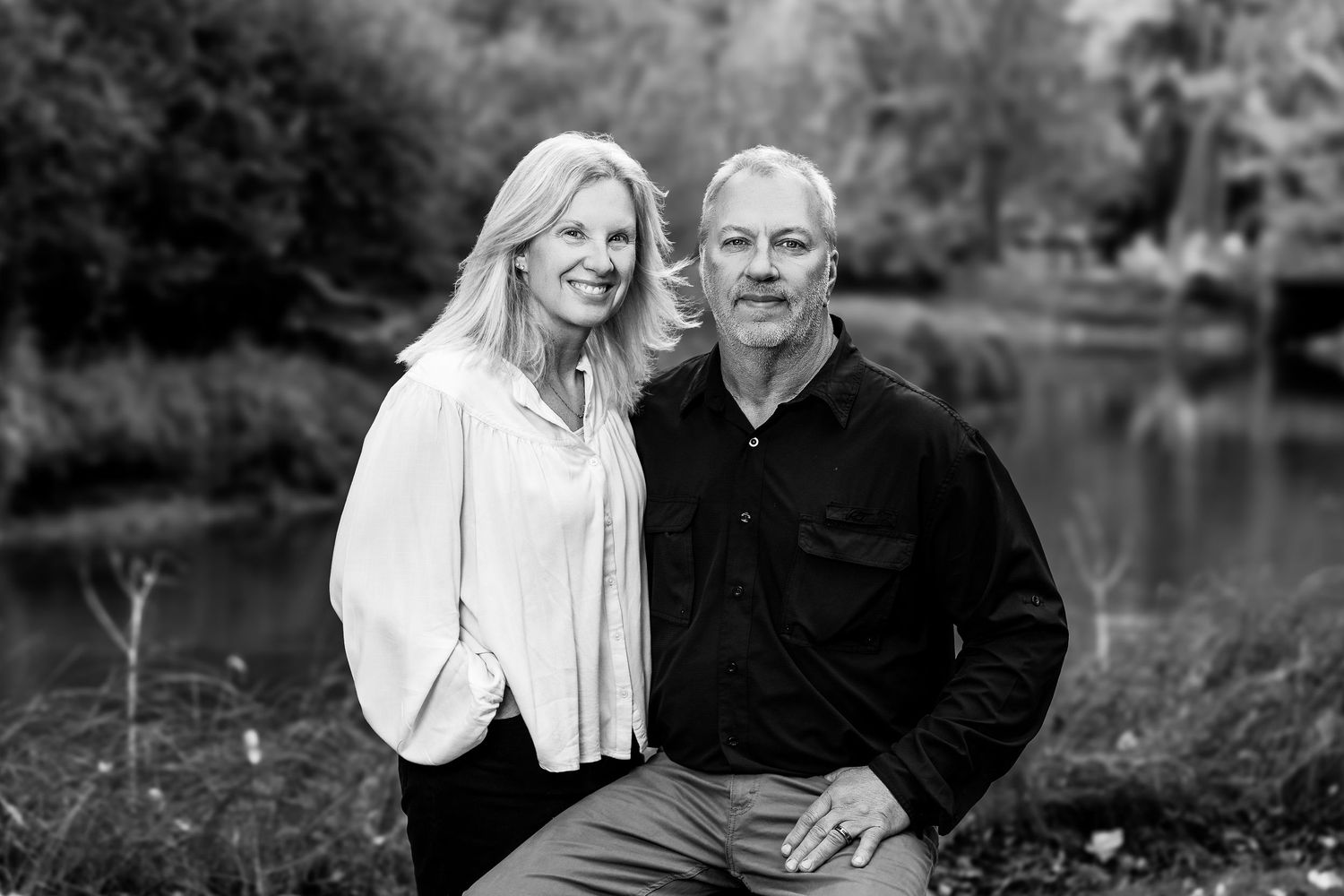 Couple sharing intimate moments by a lake during autumn photoshoot.