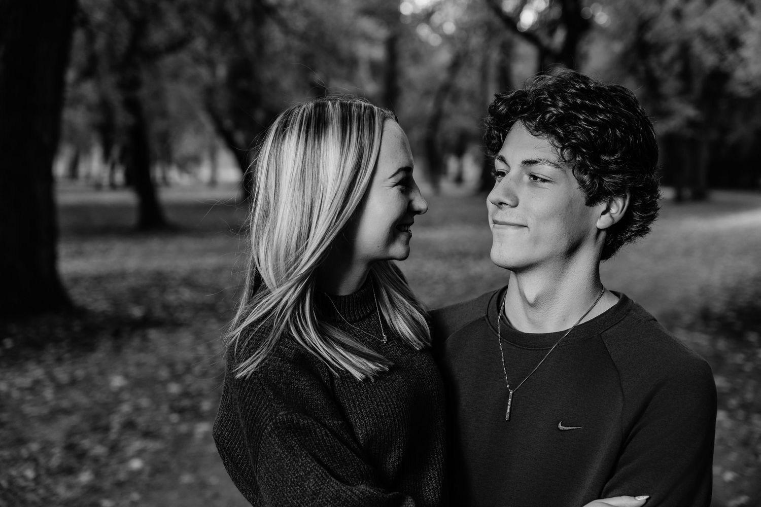 Intimate black and white portrait of a couple sharing a tender moment in a park during autumn.