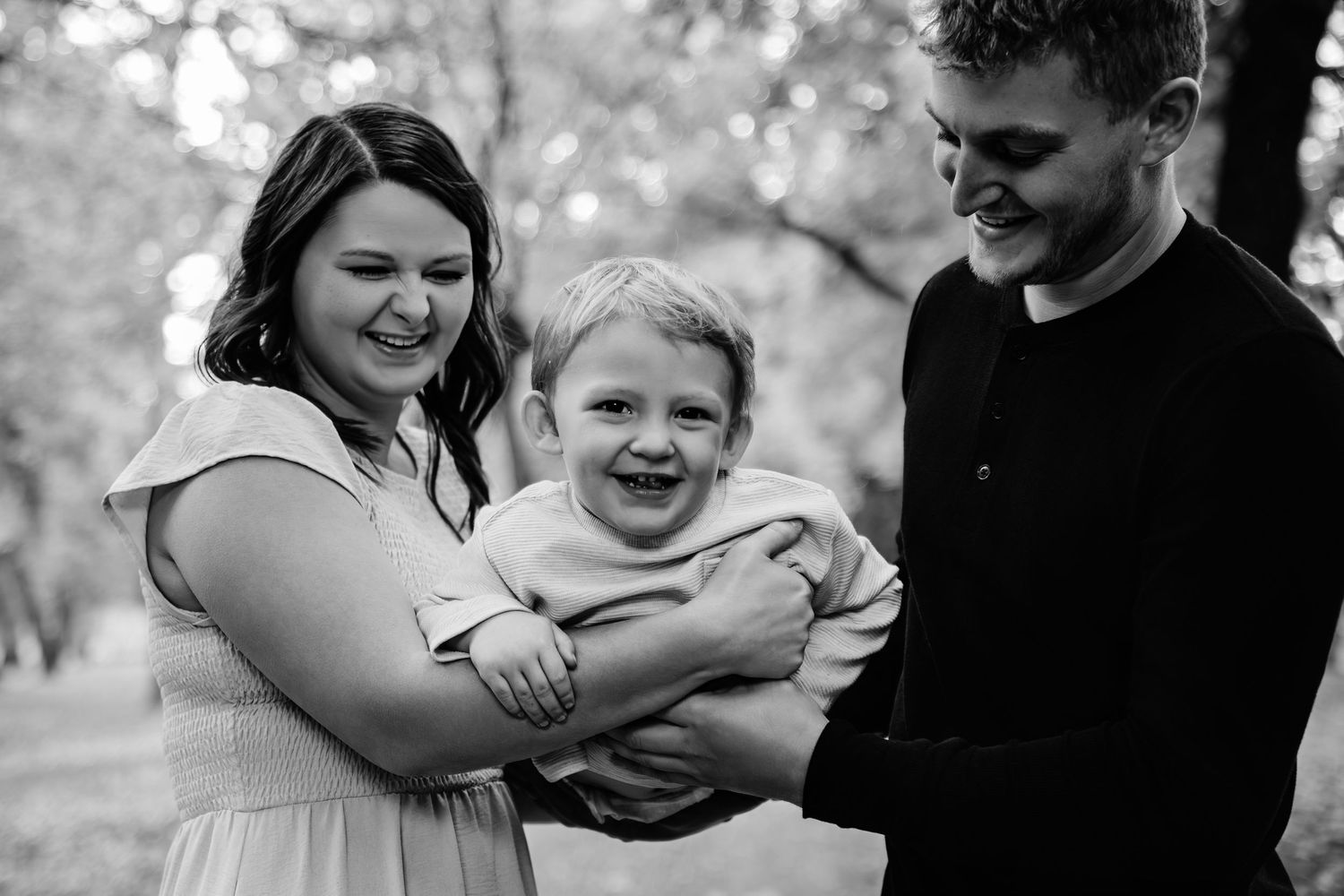 Black and white portrait of a family embracing and laughing together.