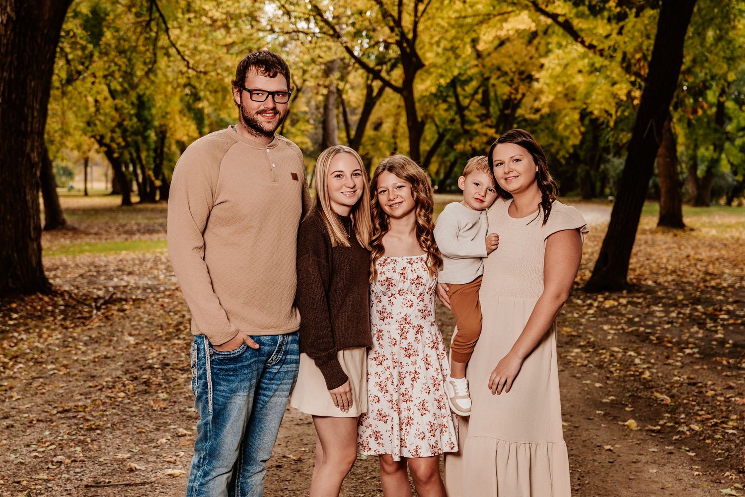 Group photo session in a park with golden autumn leaves and casual attire.