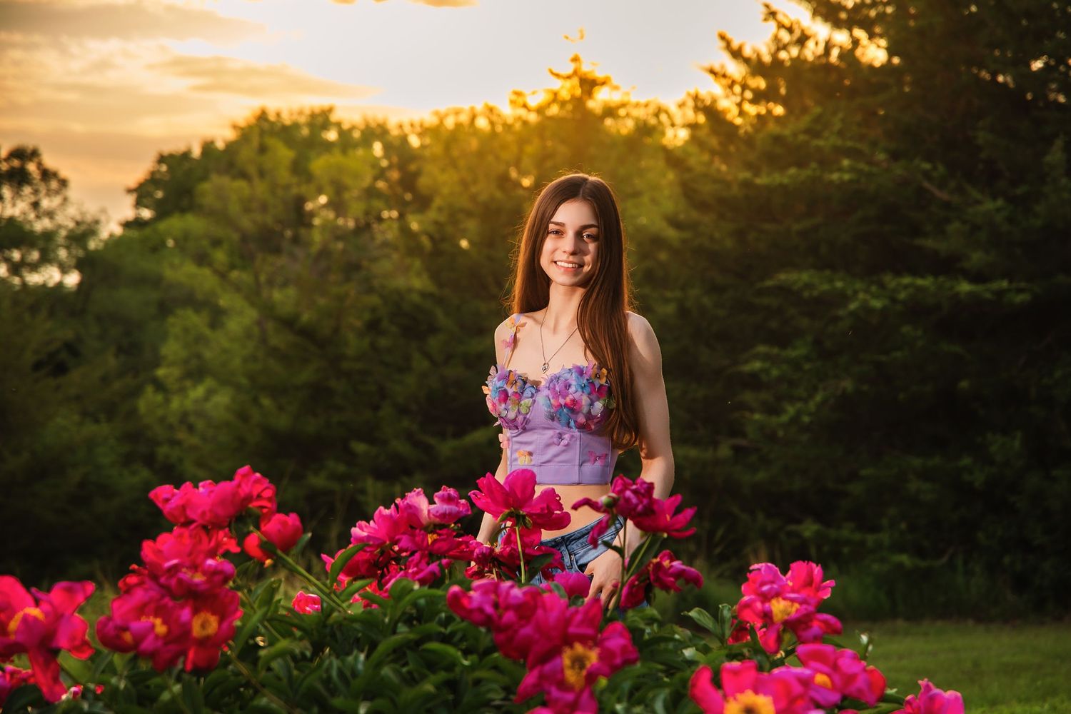 A golden sunset illuminates a garden scene with vibrant pink roses in the foreground.