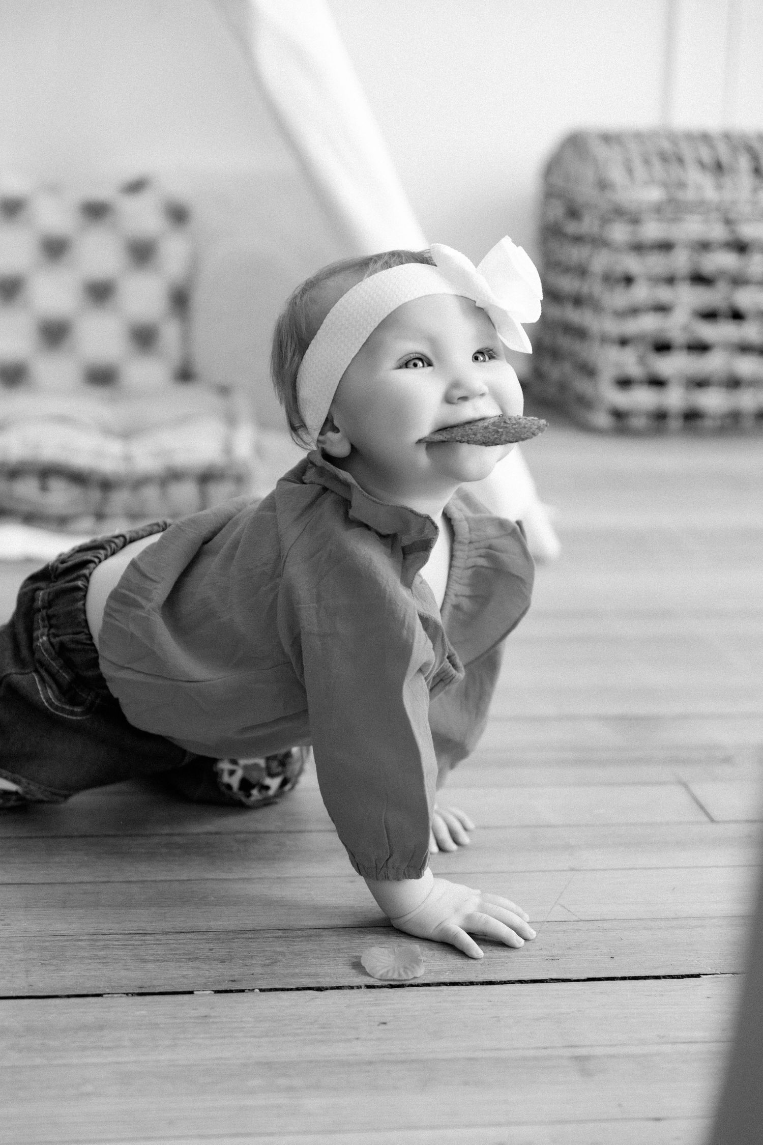 Black and white series of baby crawling on wooden floor.