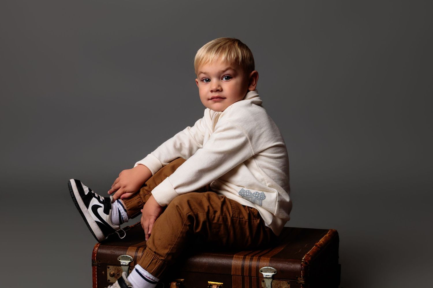 Studio photography sequence of a young child posing with a wooden storage box.