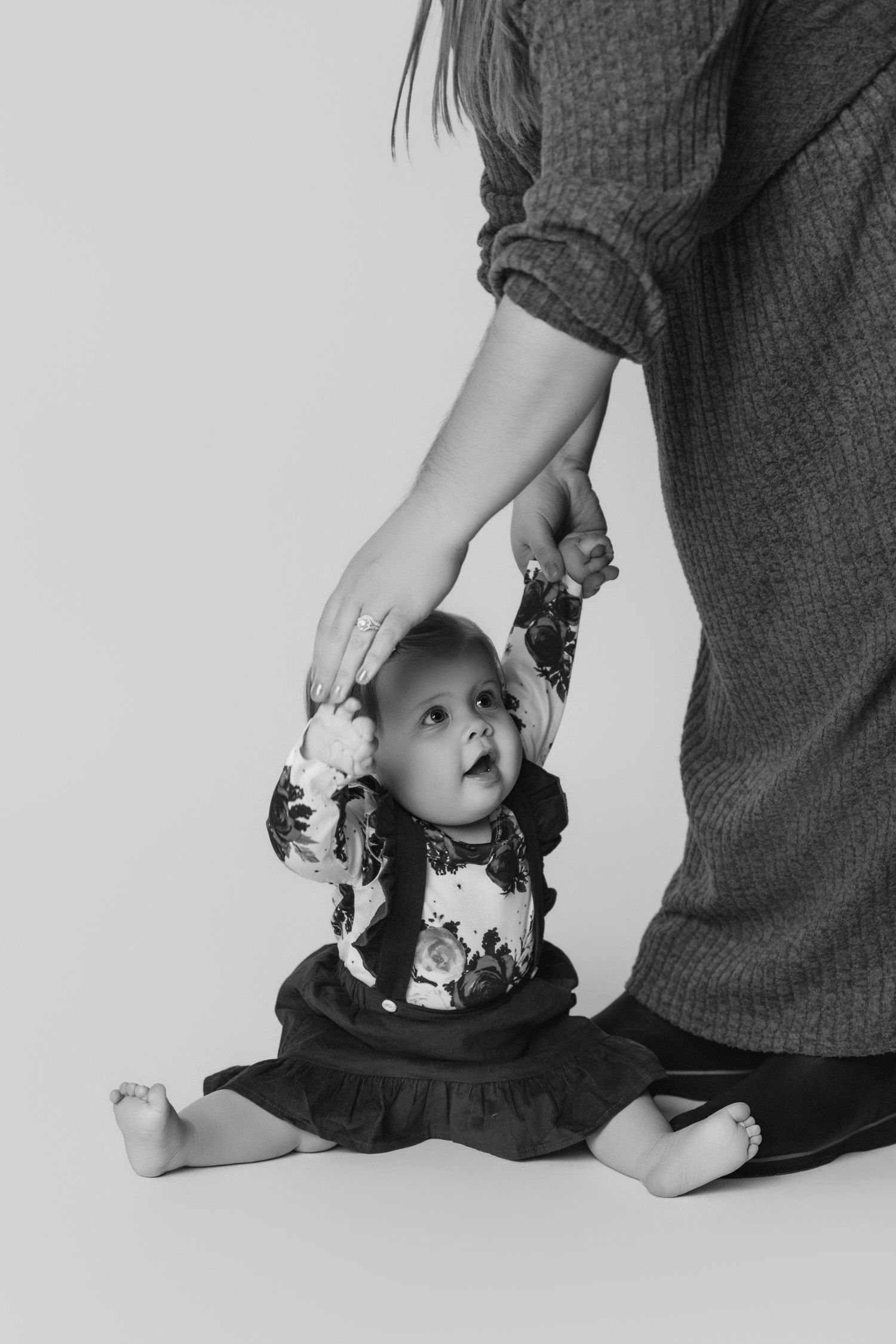 Black and white photos showing playful interaction between adult hands and a baby.