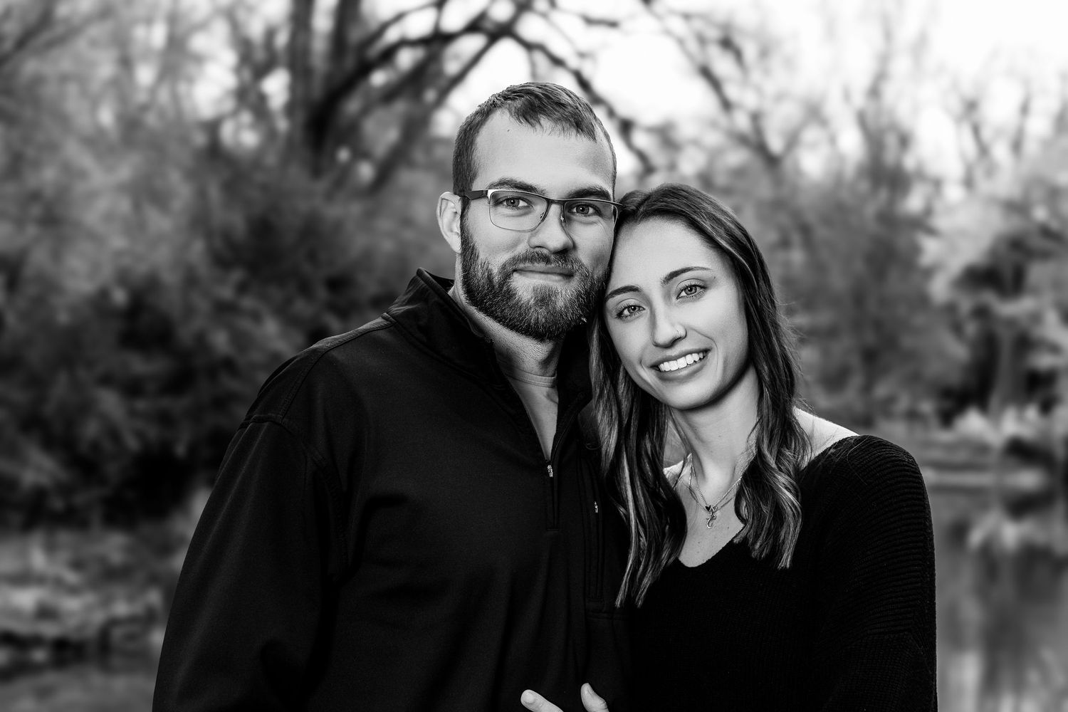 Intimate black and white portrait of a couple embracing outdoors during fall.