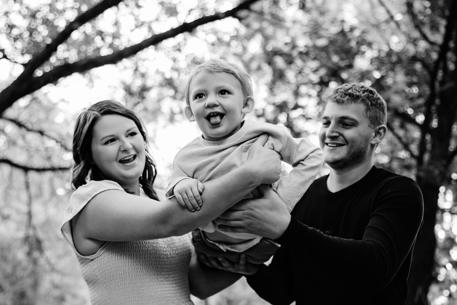 Black and white photo of a family sharing playful moments outdoors.