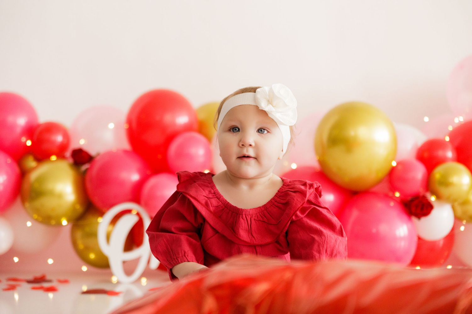Party backdrop featuring pink, red and gold balloons with sparkly decorative elements.
